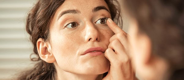 Woman examining under-eye area in mirror